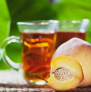 Delicious glass of juicy peach tea with fresh peaches