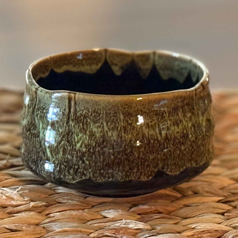 handmade ceramic matcha bowl on a woven surface with a blurred background