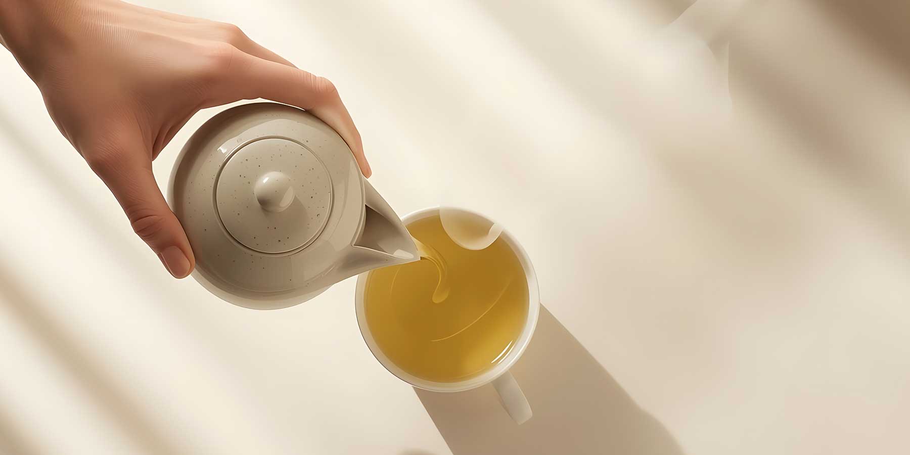 Hand pouring green tea for weightloss from a teapot into a cup on a soft beige background
