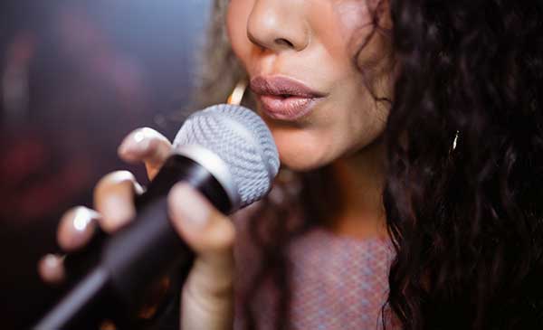Woman singing with microphone needs to know the best tea for singers
