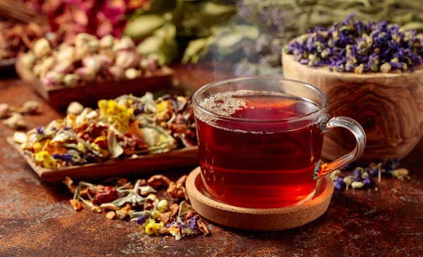 cup of herbal tea surrounded by herbs - does herbal tea have caffeine?