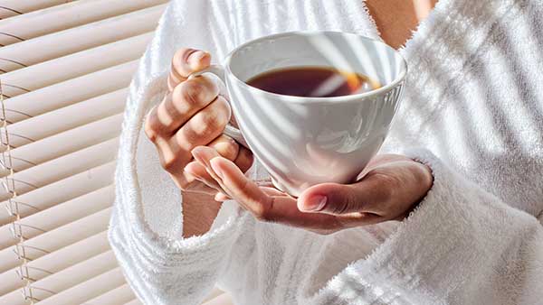 Hands holding warm mug of loose leaf tea – daily wellness ritual