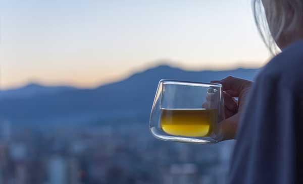 woman drinking green tea in the early morning looking over the city