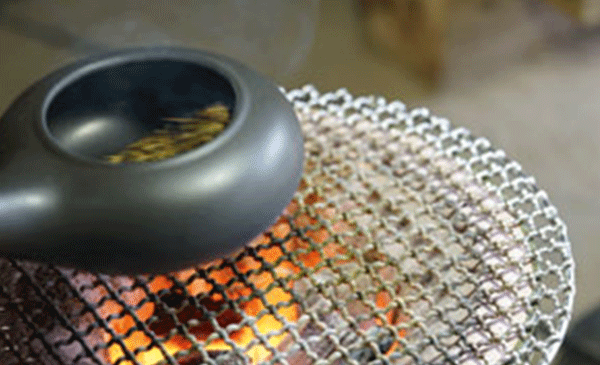 Hojicha tea roasting over charcoal in porcelain pot