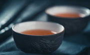 Two small black cups of flavorful oolong tea