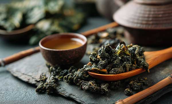 wooden spoon of iron goddess tea next to small cup of tea