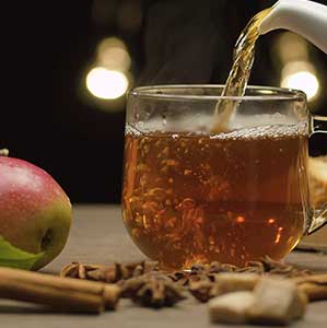 pouring hot apple teas into glass cup