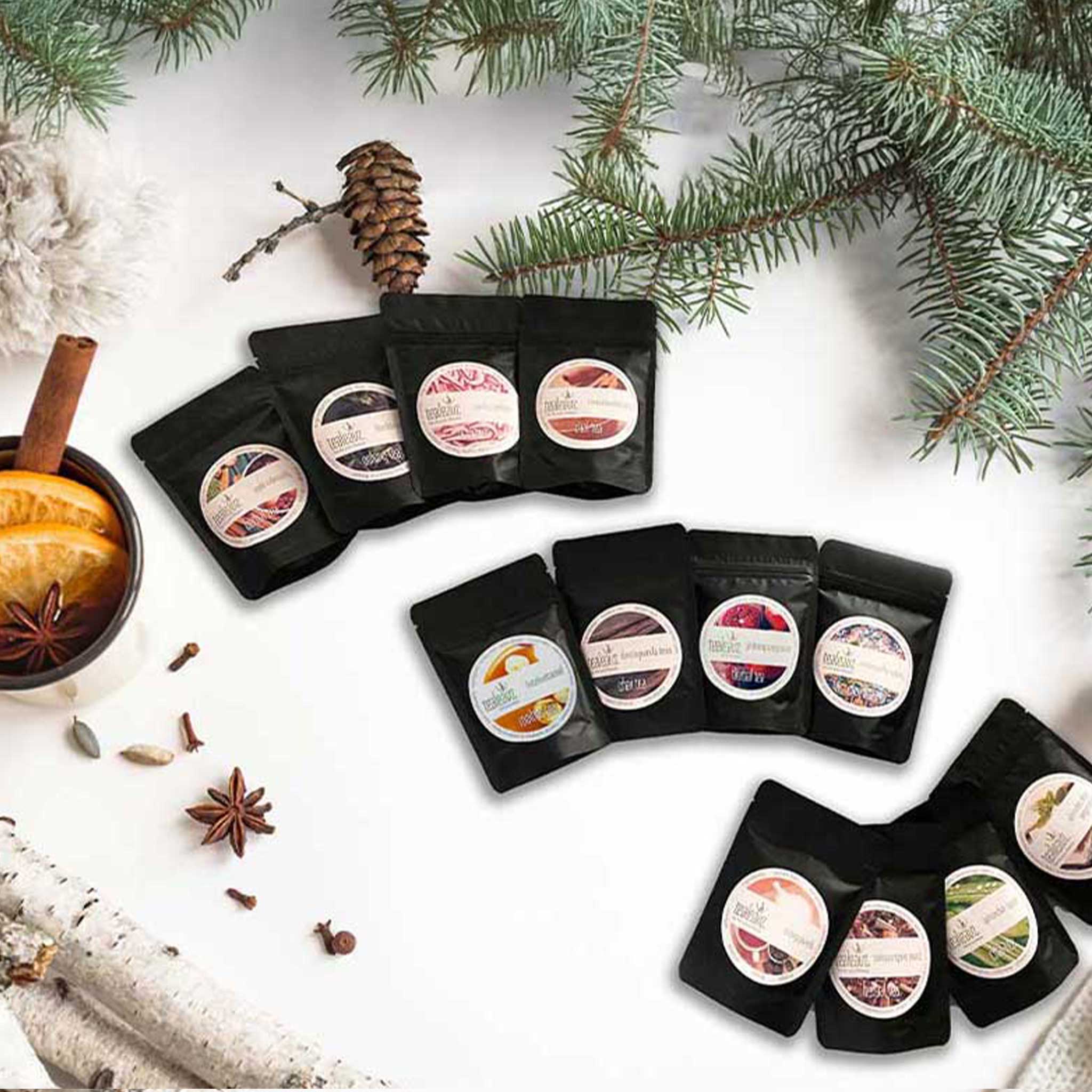 12 pouches of christmas tea arranged in a circular pattern on a white surface with festive elements.