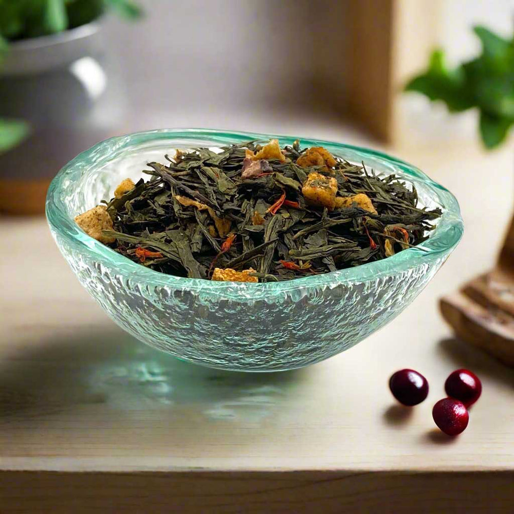 Cranberry apple green tea in a textured glass bowl on a wooden surface with cranberries alongside