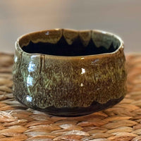 handmade ceramic matcha bowl on a woven surface with a blurred background