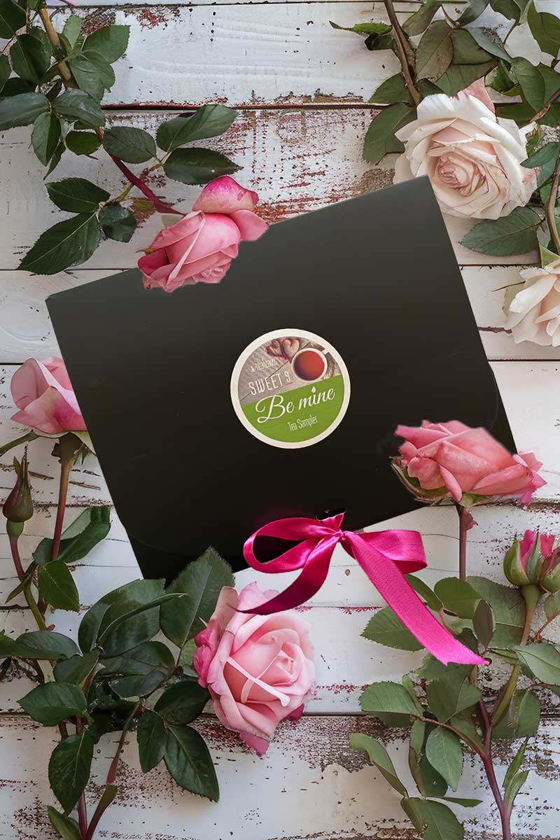 Valentine tea sampler box on a rustic wooden surface with pink flowers.