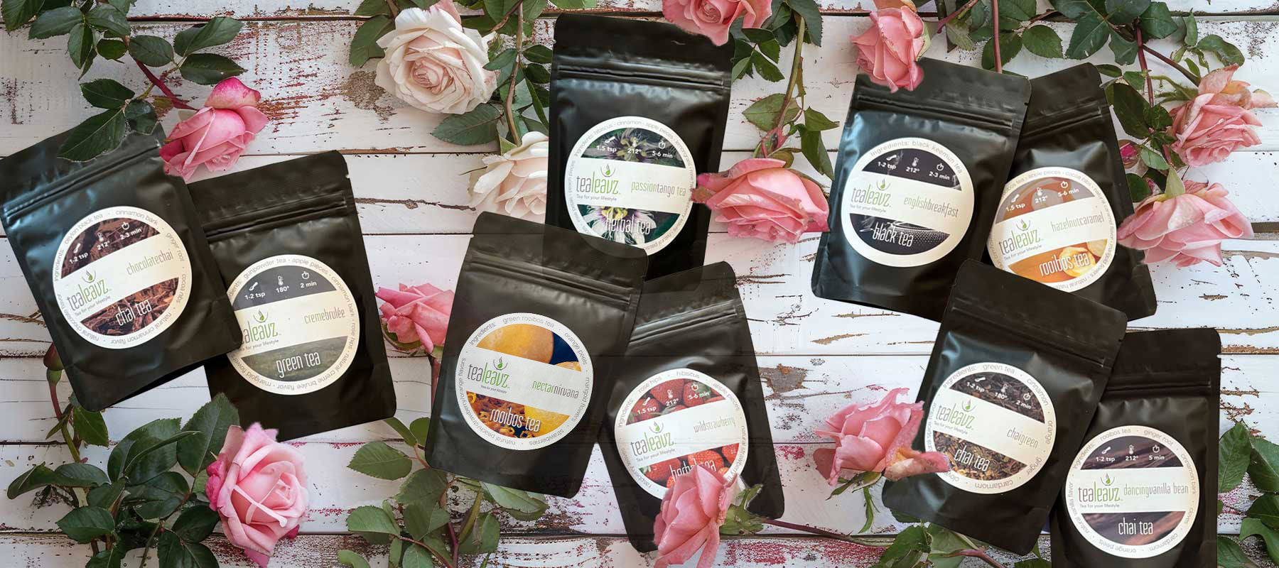 Valentine tea sampler teas on a rustic wooden surface with pink flowers.