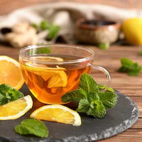 cup of jade citrus mint tea with mint leaves and lemon wedges