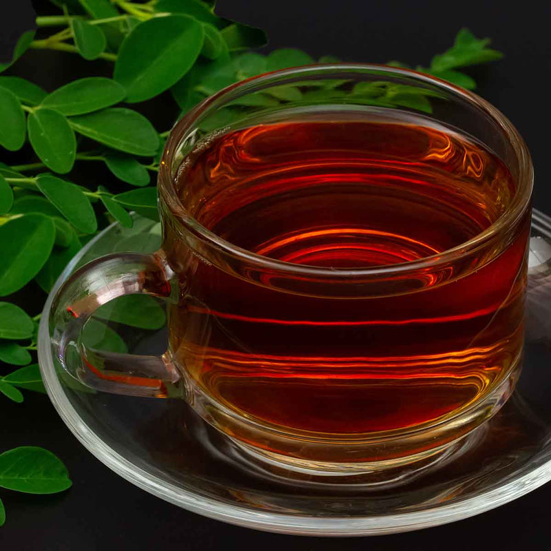 cup of strawberry moringa tea with moringa leaves